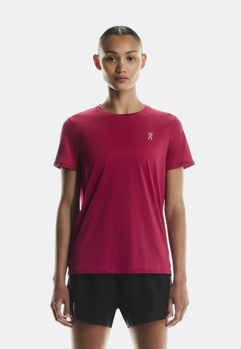 Rdeča športna majica s kratkimi rokavi in okroglim izrezom, z majhnim logotipom na levi strani prsnega koša; gladka tkanina in oprijet kroj.