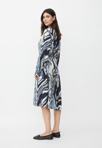 Langärmliges Kleid mit einem blau-weißen Marmor-Muster, in der Taille gerafft, mit einer Midi-Länge und fließender Stofftextur.