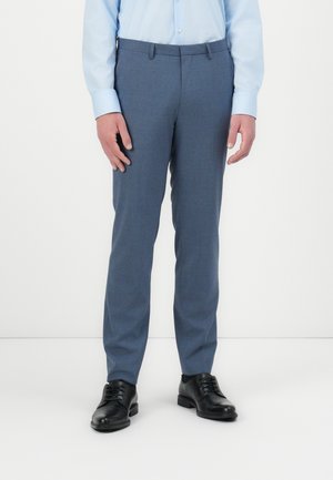 Pantalones de vestir azul a medida en una tela suave, con frente plano, presillas para el cinturón y corte ajustado, combinados con zapatos de vestir negros.