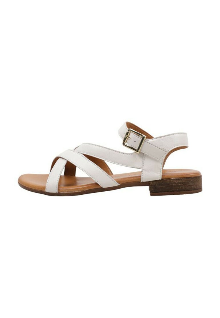Sandale en cuir blanc avec des brides croisées, boucle réglable à la cheville et un petit talon en bois brun. Semelle plate pour le confort.