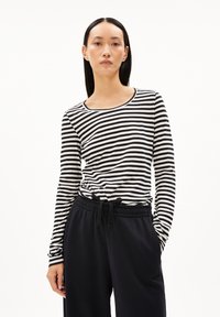Schwarz-weißer gestreifter langärmeliger Oberteil mit rundem Ausschnitt, kombiniert mit dunklen, elastischen Hosen mit einem Kordelzugbund.