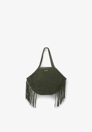 Bolso macramé verde oliva con correa para el hombro y largas borlas con flecos en ambos lados, con una pequeña etiqueta rectangular de la marca.