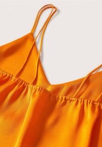 Camiseta sin mangas de un brillante color naranja que presenta finas tirantes de espagueti, un escote en V y detalles fruncidos en el busto para agregar textura.