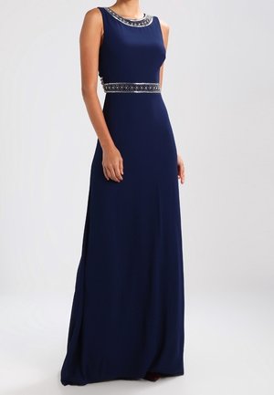 Robe de soirée sans manches bleu marine avec encolure et taille ornées de perles, longueur au sol, portée par une femme debout.