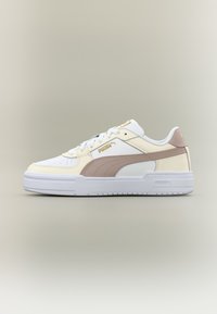 Λευκό και μπεζ χαμηλό sneaker Puma με διάτρητη μύτη, καφέ λογότυπο ρίγα στο πλάι, λευκά κορδόνια και λευκή σόλα σε απλό φόντο.