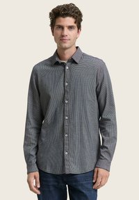 Camisa de manga larga a cuadros en blanco y negro con collar de botón, material de algodón, tejido texturizado y botones blancos.