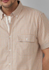 Korte mouwen geruit shirt in lichtoranje en wit, met een button-down kraag en een borstzakje aan de linkerkant.