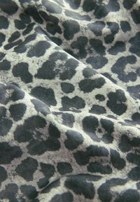 Material cu model leopard neregulat negru și alb, prezentând falduri moi și textură.