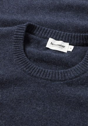 Navyblauer Pullover aus weicher Wolle. Verfügt über einen gerippten Rundhalsausschnitt und ein Etikett mit "hessnatur" in Weiß auf der Innenseite des Halsabschlusses.