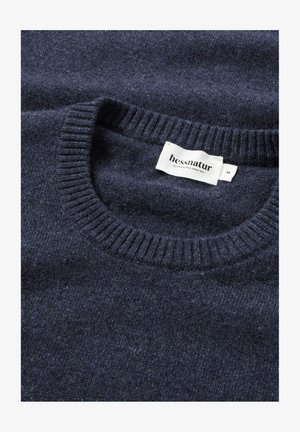 Navyblauer Pullover aus weicher Wolle. Verfügt über einen gerippten Rundhalsausschnitt und ein Etikett mit "hessnatur" in Weiß auf der Innenseite des Halsabschlusses.