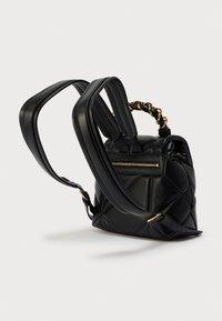 Μαύρο δερμάτινο σακίδιο με καπιτονέ σχέδιο, που διαθέτει έναν χρυσό αλυσίδα στο πάνω χερούλι και ρυθμιζόμενους μακριούς ιμάντες, καθώς και μια πίσω τσέπη με φερμουάρ.