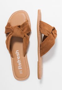 Braune Wildleder-Sandalen mit einem geknoteten Schleifen-Design und einer tan-farbenen synthetischen Sohle. Weiße Nähte betonen die Kanten. Das Etikett lautet "Refresh."