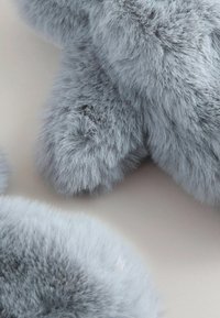 Gray faux fur fabric with a soft, fluffy texture. Features rounded edges and a slight sheen. Accents in varying shades of gray.
