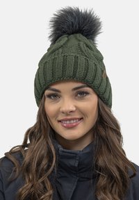 Gorro de punto verde oscuro con textura acanalada y un pompón de piel sintética en la parte superior. Incluye un pequeño parche de logo marrón en el lado.