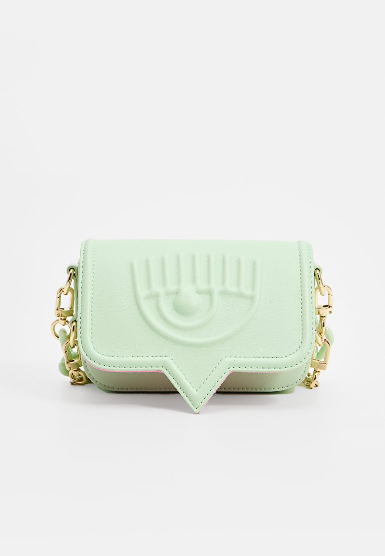 Bolso cruzado de color verde menta, texturizado, con un diseño de ojo en relieve, herrajes dorados y correa de cadena. Presenta un cierre de solapa y un ribete en contraste.