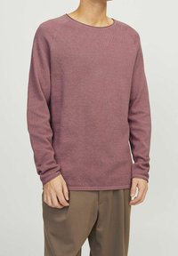 Langärmliger Pullover mit Rundhalsausschnitt in strukturiertem, staubrosa Farbton. Hergestellt aus weichem Material mit gerippten Bündchen und Saum, kombiniert mit weiten beigen Hosen.