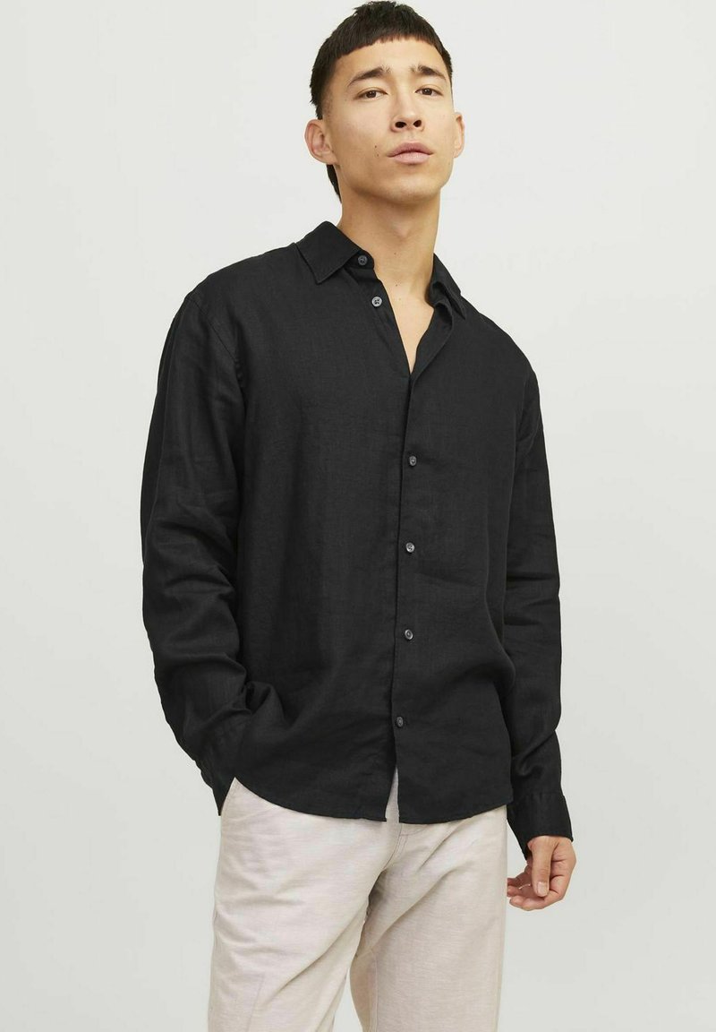 Camisetta nera a maniche lunghe in lino con colletto a bottoni e una sottile texture. Presenta cinque bottoni lungo la parte anteriore.
