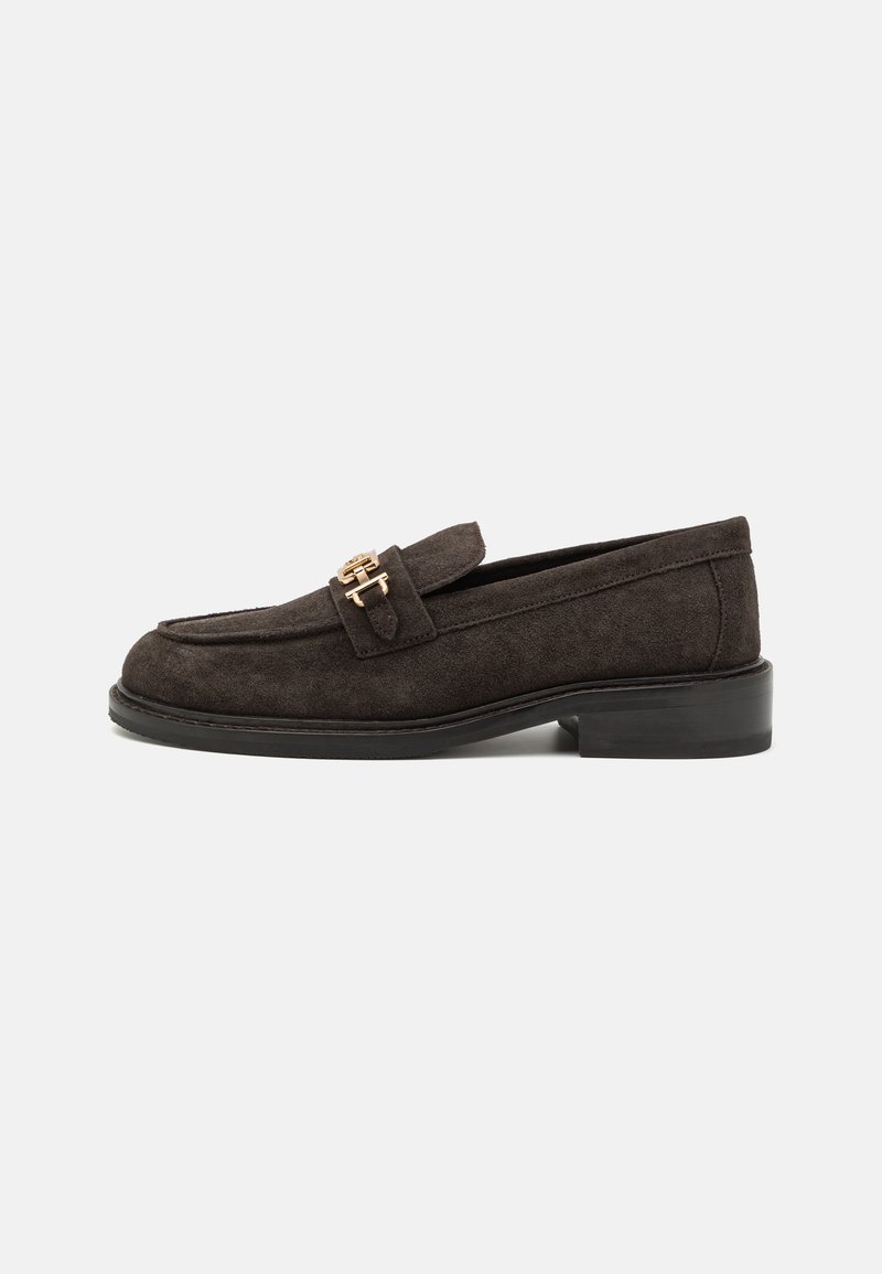 Dunkelbraune Wildlederloafer mit niedrigem Blockabsatz, ausgestattet mit einem goldfarbenen Hardware-Akzent an der Vorderseite und einem gesteppten Design entlang der Oberseite.