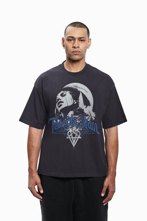 Camiseta gráfica negra con un diseño ilustrado de un rostro con rayas y el texto "Lágrimas en la lluvia" en azul y plata, corte oversize.