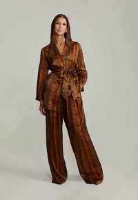 Brown patterned loungewear set with an orange stripe, features a belted wrap top and wide-leg pants in a smooth, silky fabric.