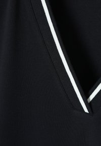Tissu noir avec un décolleté en V, présentant une bordure striée blanche le long du bord. Texture lisse, design minimal.