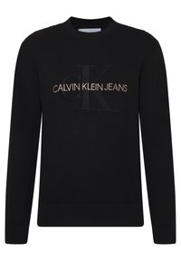 Pull en maille noire à manches longues, avec un logo CALVIN KLEIN JEANS en relief en lettres métalliques dorées sur la poitrine.