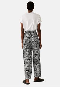 Schwarz-weiße gemusterte weite Hose mit hoher Taille, aus leichtem Stoff, mit lockerer Passform und seitlichen Taschen.