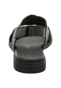 Schwarze Ledersandale mit flacher Sohle, verstellbarem Riemen und offenem Rückendesign. Merkmale sind eine glatte Textur und minimalistische Details.