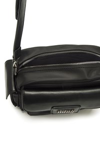 Borsa nera con finitura in pelle martellata, dotata di un scomparto con zip e di una tracolla removibile. Design elegante, con pochi dettagli in metallo.
