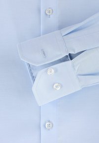 Lichtblauw gestructureerd overhemd met spitse manchetten, voorzien van witte knopen en een subtiel geweven patroon. Manchetdetail zichtbaar, met zichtbare stiksels.