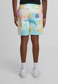 Shorts i pastelfarvede tie-dye nuancer af blå, gul og pink, lavet af blødt materiale, med elastisk talje og en baglomme med branding.