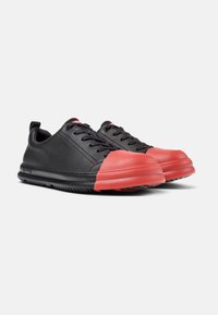 Schwarze Ledersneaker mit einem roten Gummi-Zehenschutz und schwarzer Sohle. Mit strukturiertem Obermaterial, Schnürsenkeln und einer kleinen Fersenschlaufe.
