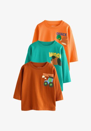 Tre långärmade bomullsskjortor: orange med en anka-grafik, teal med en hund och "WOOD", samt rostfärgad med en traktor-grafik.