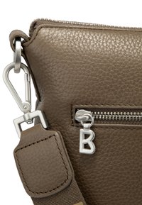 Brun strukturerad läderhandväska med silverdetaljer, dragkedjestängning och ett avtagbart bälte med ett spänne och en dekorativ "B" dragkedjehandtag.