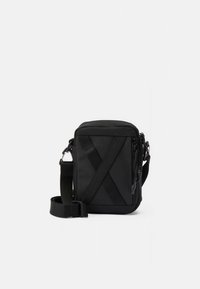 Zwarte nylon crossbodytas met een eenvoudige rechthoekige vorm, voorzien van diagonale bandjes aan de voorkant, verstelbare riem en ritssluiting.