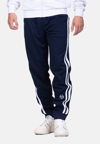 Marine blauwe sportbroek met witte zijstrepen, elastische boorden en logo-detail. Gemaakt van zachte stof, ontworpen voor comfort en beweging.