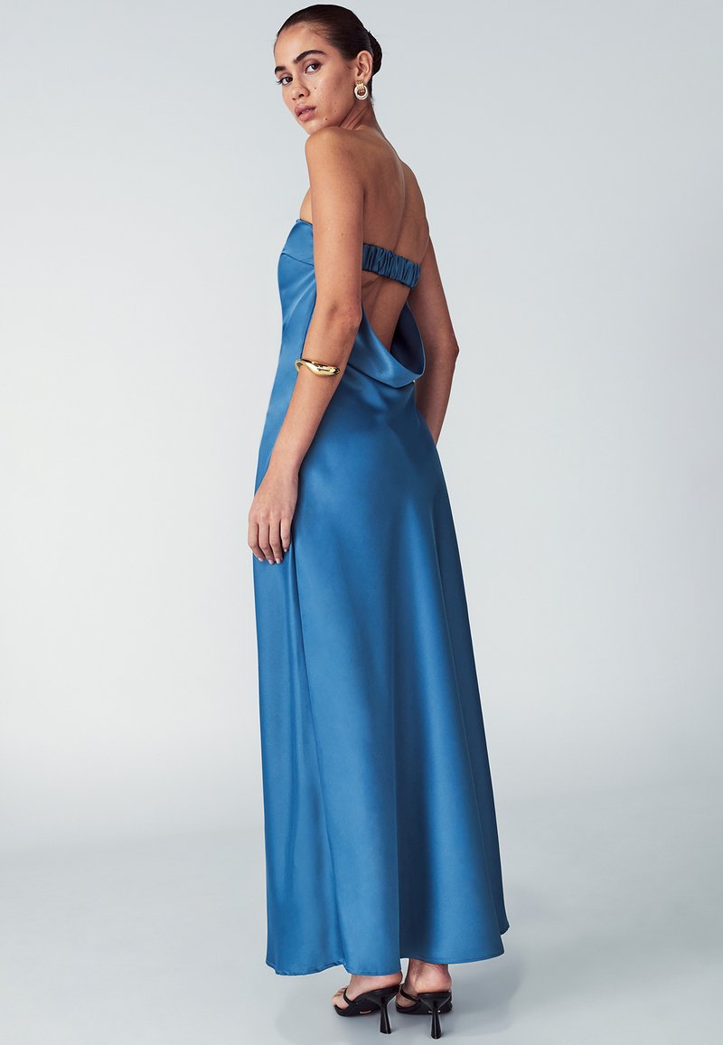 Brezramni, kobaltno moder satenast obleka z nabranim hrbtom in odprto zasnovo hrbta. Dolga do tal, z gladko teksturo in elegantnim padanjem.