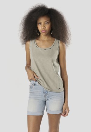 Svetlo siva majica brez rokavov z okroglim izrezom in okrasnimi zakovicami, kombinirana z zavihanimi kavbojskimi kratkimi hlačami. Mehka tkanina in sproščen kroj.