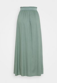 Grüne Maxiröhre aus weichem, leichtem Stoff. Sie besitzt einen elastischen Bund mit Rüschendetails und einen fließenden, geraden Schnitt.