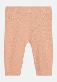 Persikų spalvos megzti kelnės su tekstūruotu raštu, turinčios skeltą juosmenį ir mažą išsiuvinėtą logotipą priekyje.