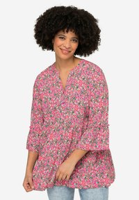 Blouse florale rose avec un décolleté en V, des manches volantes et une coupe ample. Présente de petits motifs de fleurs multicolores sur un fond clair.