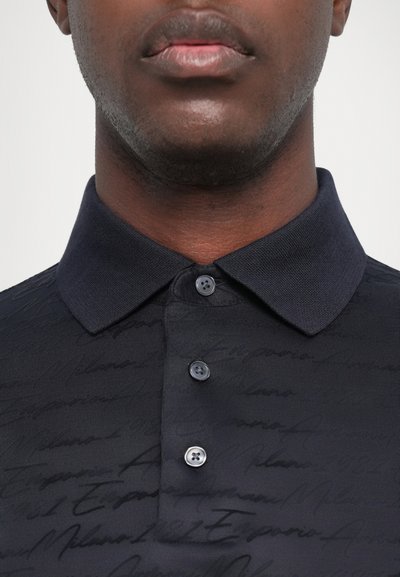 Svart polo skjorte med et teksturert design og et subtilt skriptmønster, tre-knapps placket og en klassisk krage.