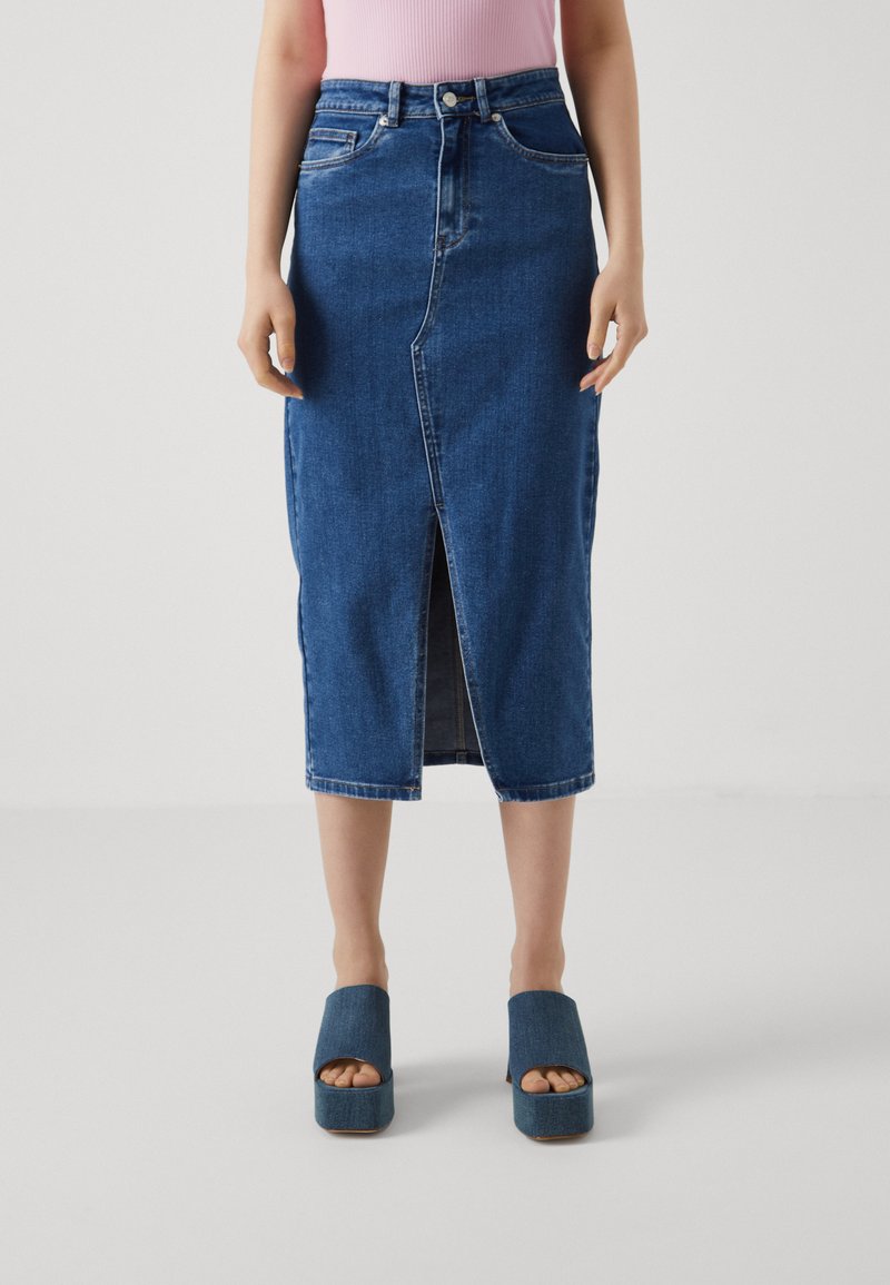 Denim midi-hame, jossa on etuleikkaus, korkea vyötärö ja klassiset ompeluyksityiskohdat. Yhdistetty tummiin alustasaappaisiin, jotka ovat yhteensopivat denimin kanssa.