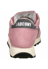 Ružičasta suede atletska cipela s sivoj peti, brendirana "SAUCONY" u bijeloj boji. Ima podstavljeni ovratnik i teksturiranu crnu gumu na potplatu.
