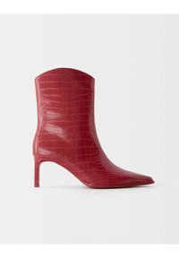 Red crocodile-embossed ankle boot with a pointed toe and slim heel. Smooth texture, structured silhouette, and shiny finish.