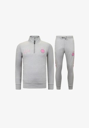 Lichtgrijs trainingspak met een lange mouwen top met een kwart-ritssluiting en joggerbroek met een trekkoord, beide met roze logopatches en kleine designs.