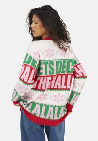 Maglione lavorato a maglia grossa bianco con accenti rossi, verdi e rosa; motivi festivi con testo e fiocchi di neve; collo tondo; vestibilità comoda; maniche lunghe.