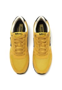 Zapatillas amarillas que combinan materiales de ante y malla, con puntera redonda, sistema de cordones y suela de goma negra. Acabadas con un logo.