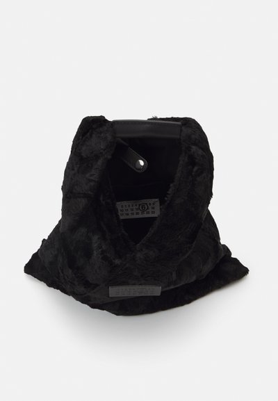 Bolsa de pêlo sintético preto com uma textura suave, forma triangular e fecho de zip no topo. O interior inclui uma etiqueta com métricas de tamanho e um revestimento preto.