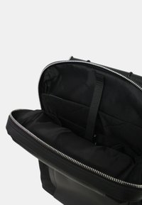 Borsa nera con zip, dotata di un esterno texturizzato. L'interno presenta una fodera in tessuto, diverse tasche e una chiusura a zip liscia.